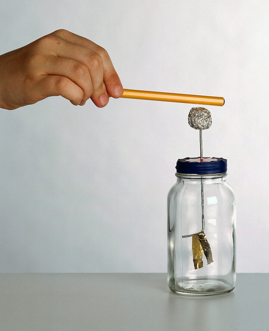 Hand holding pen above foil ball appearing out of jar