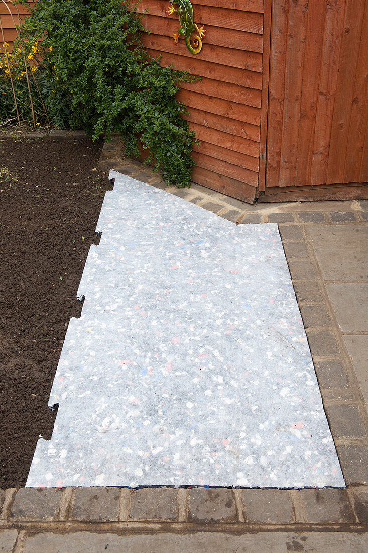 Layer of shock-absorbing material laid in place in garden