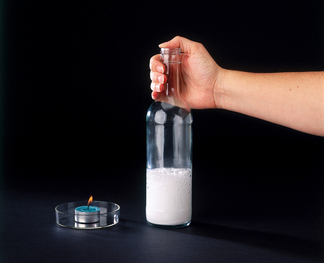 Hand holding bottle filled with white liquid