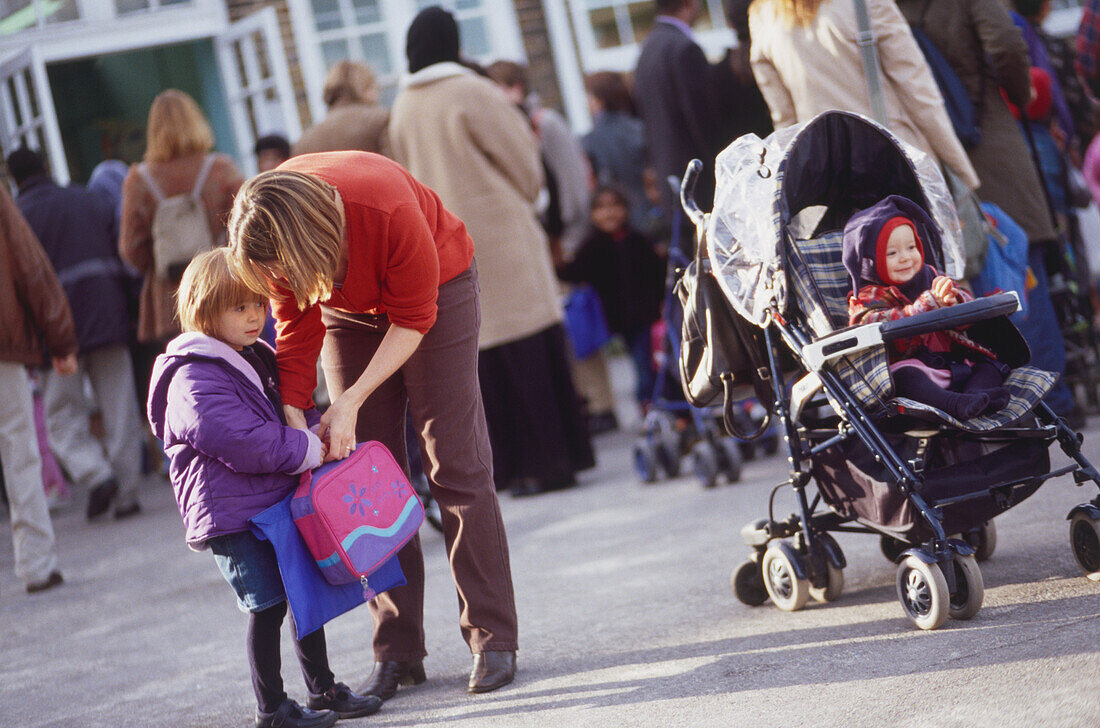 Woman bending over a child carrying a bag