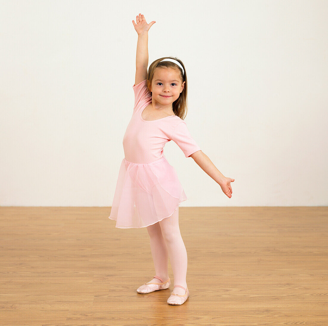 Girl in ballerina outfit holding one arm up