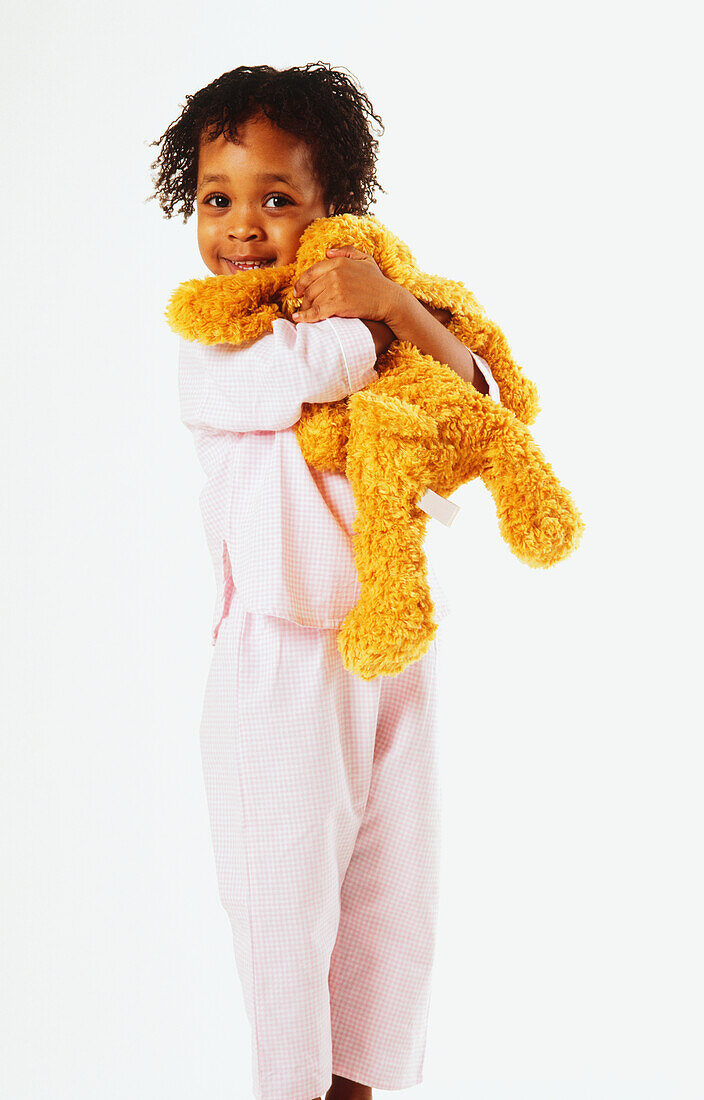 Standing girl cuddling yellow soft toy