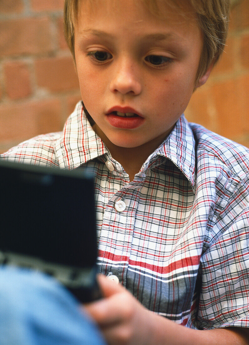 Boy playing on a hand held computer game