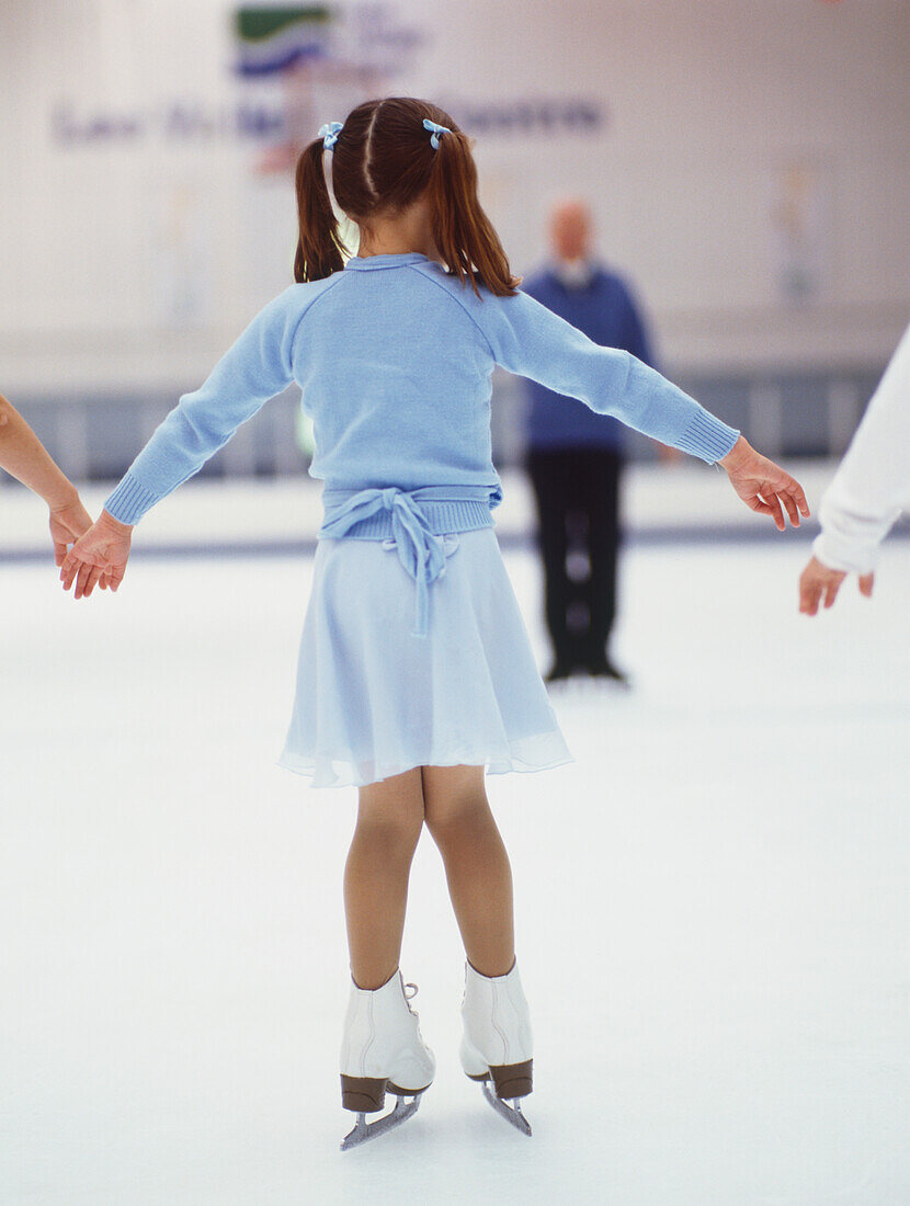 Young ice skater holding on to two companion's hands