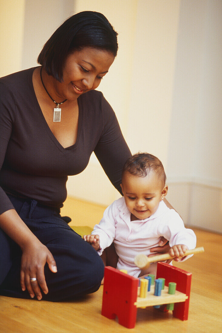 Woman sitting on floor with arm around playing child