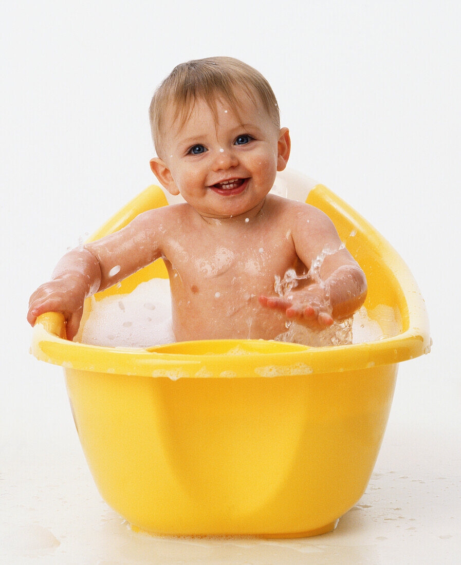 Smiling baby girl in yellow bath tub
