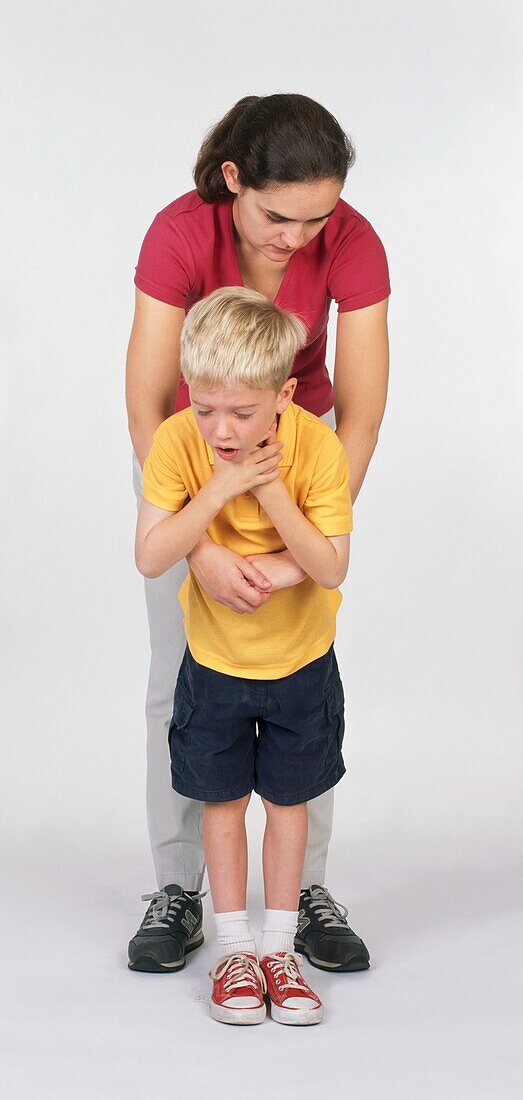 Woman holding arms around choking boy