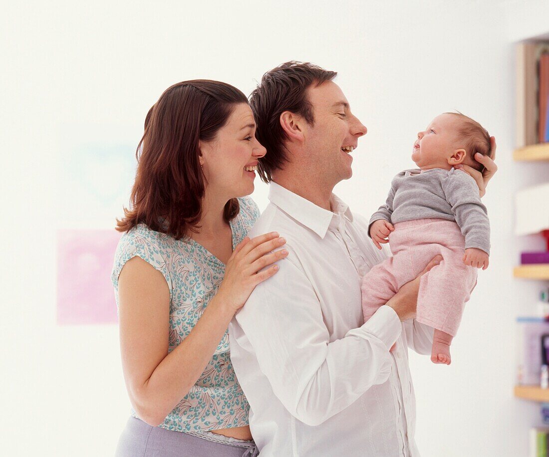 Couple smiling at baby being held securely by man