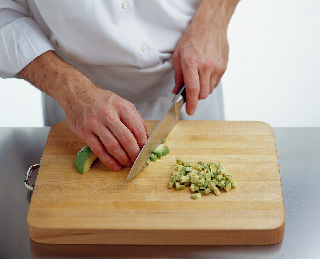 Using kitchen knife to slice avocado into small pieces
