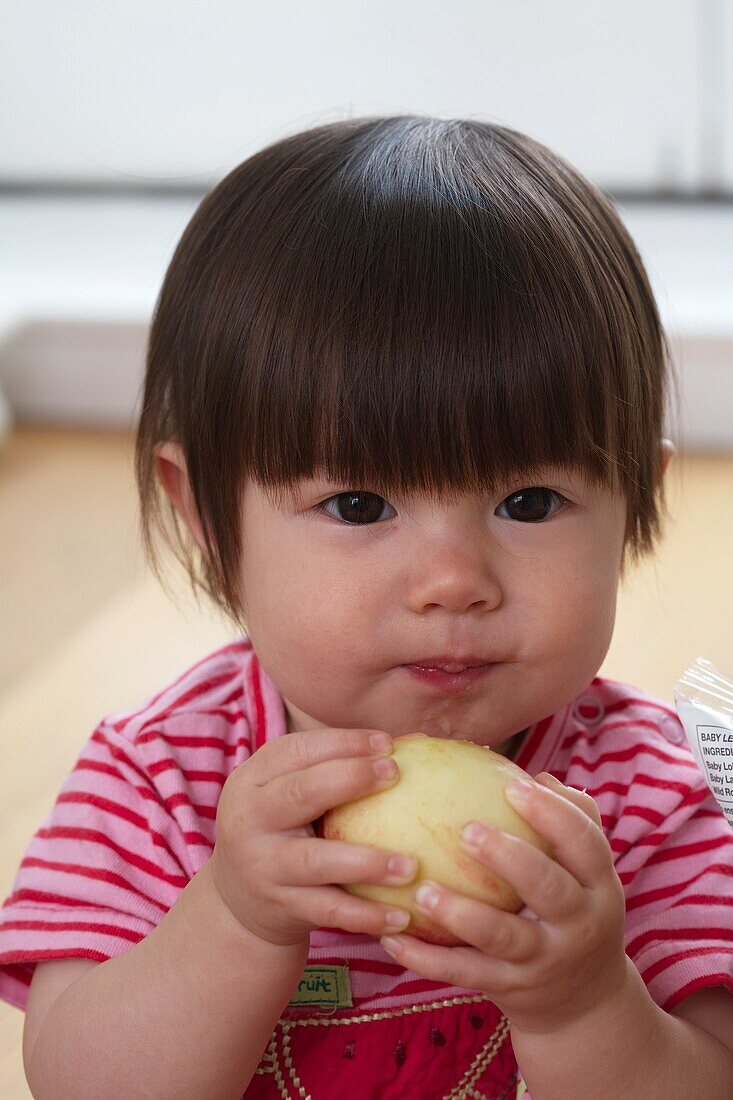 Baby girl holding a peeled apple