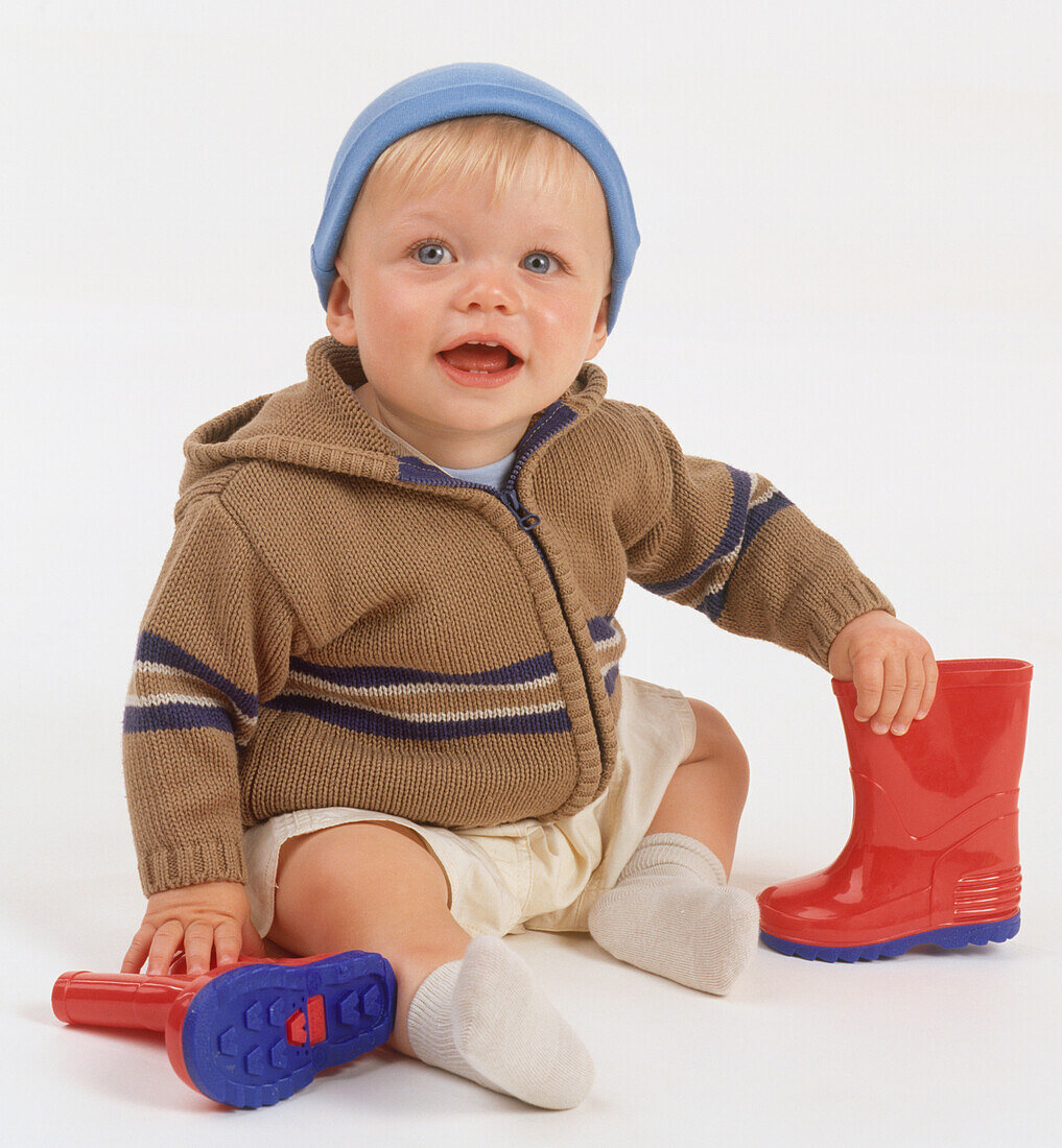 Boy sitting on the floor holding wellies