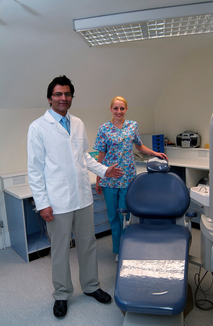 Dentist and dental nurse standing next to dentist's chair