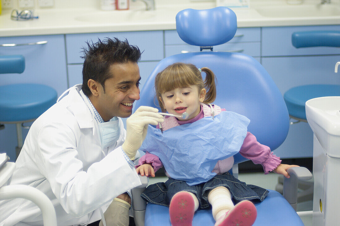 Dentist examining girl's teeth with angled mirror