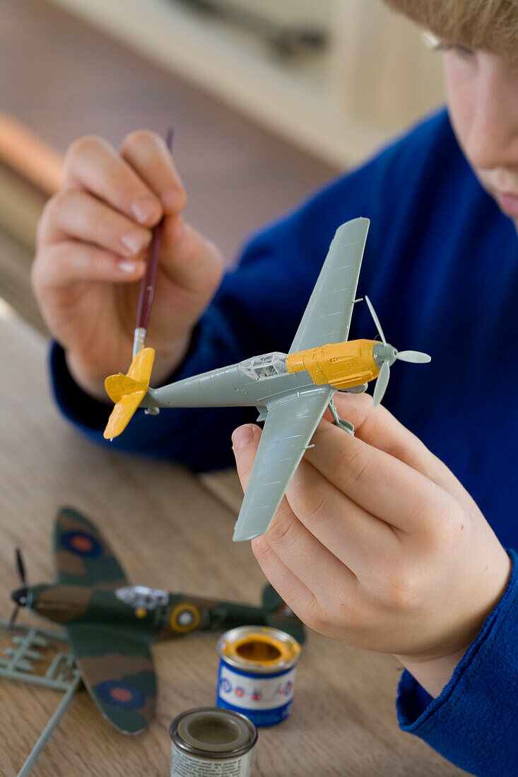Boy painting model airplane yellow
