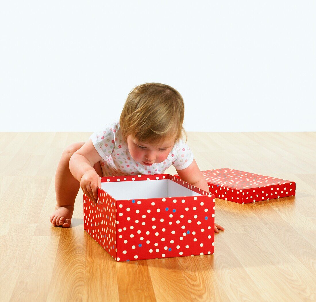 Baby girl looking inside an open box