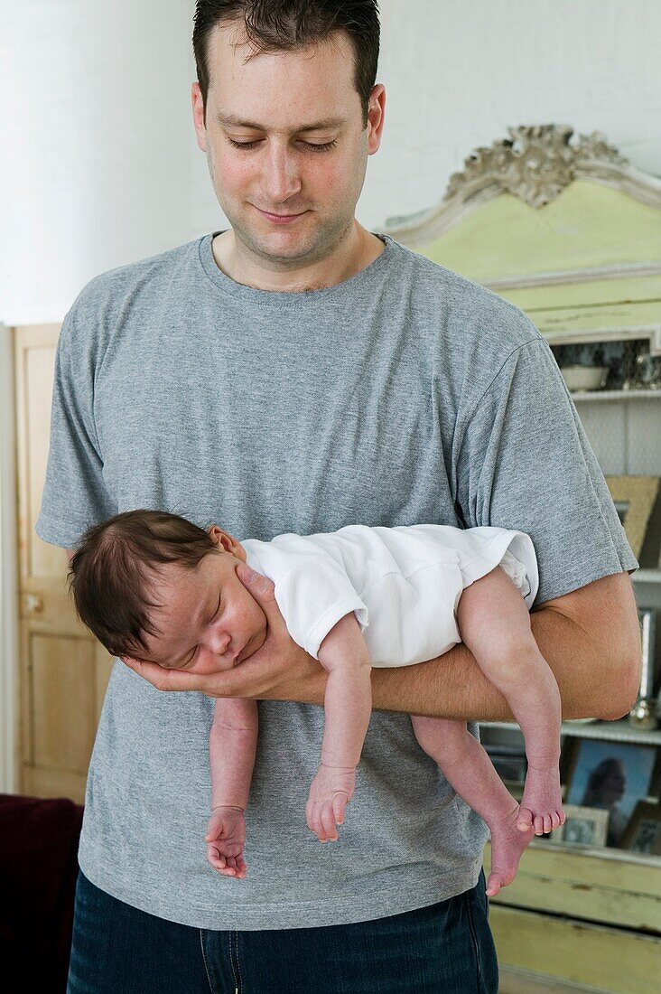 Baby boy lying asleep on man's arm