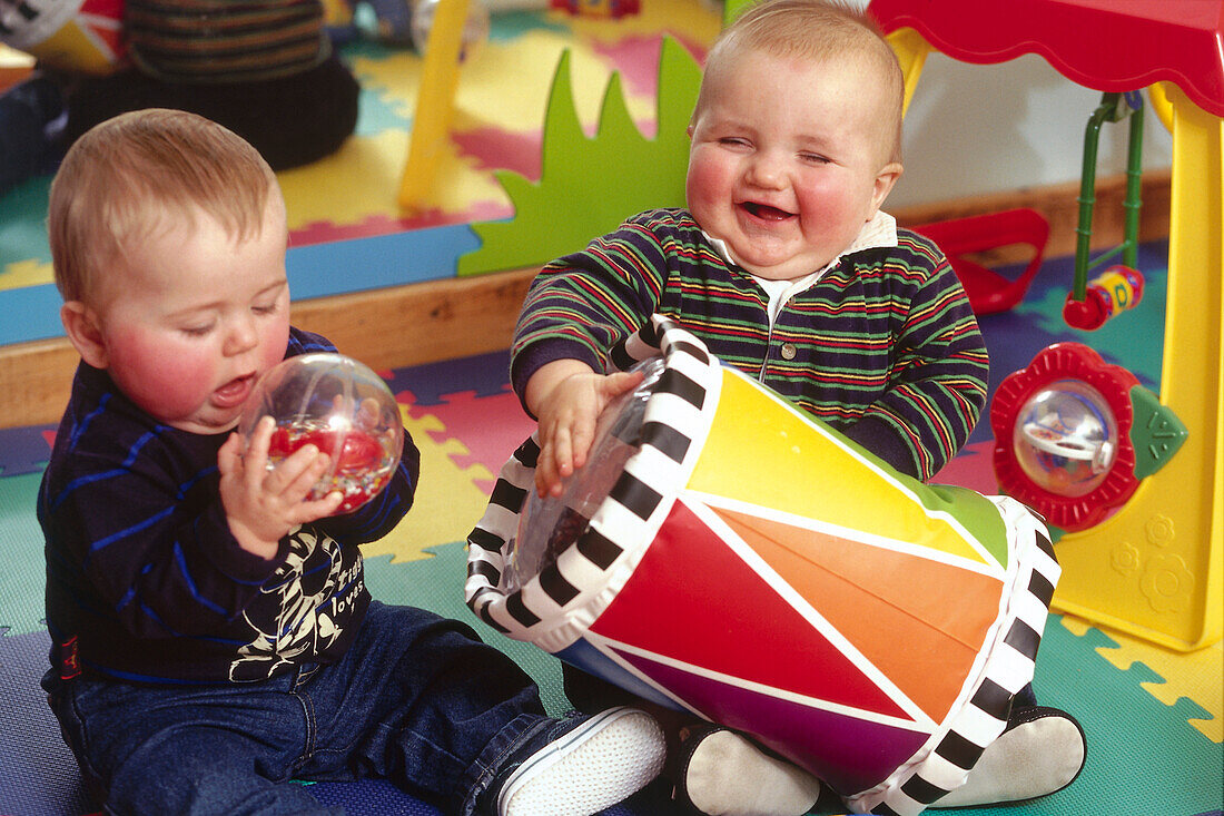 Two boy toddlers playing on foam puzzle mat