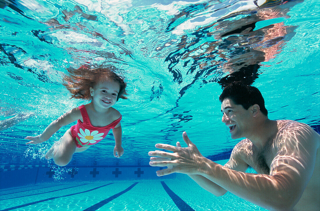 Father and daughter swimming underwater
