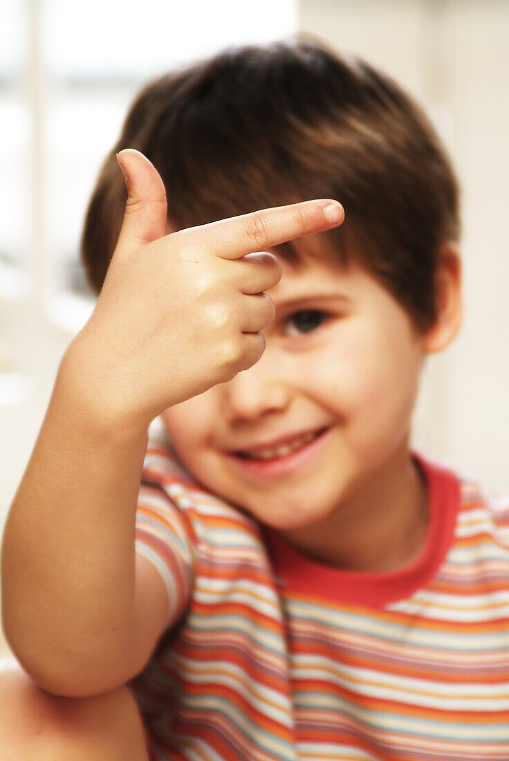 Boy holding one finger up pointing to the side