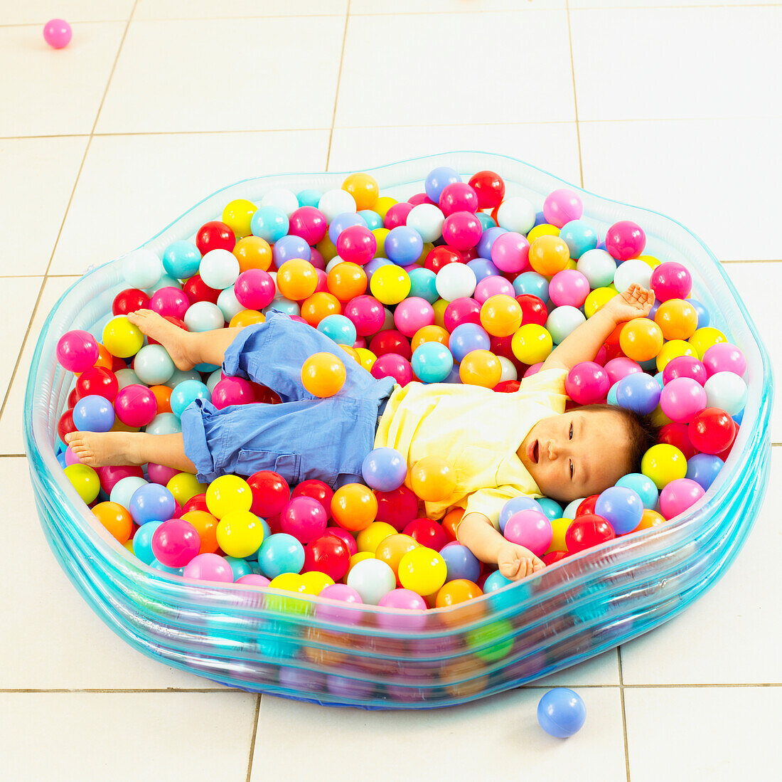 Boy amongst balls held in a large plastic swimming pool