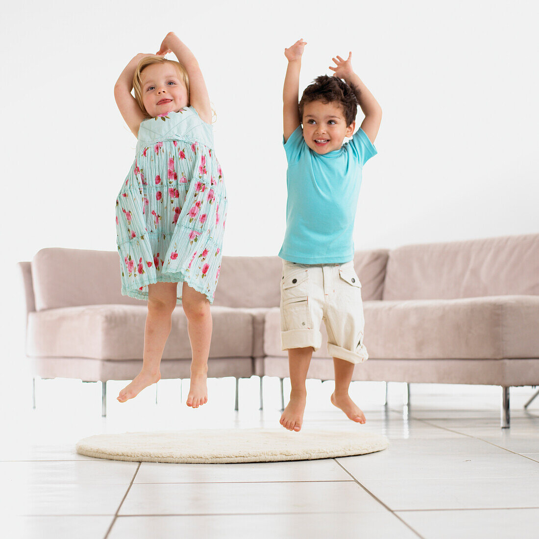 Girl and boy jumping up from a rug in a living room