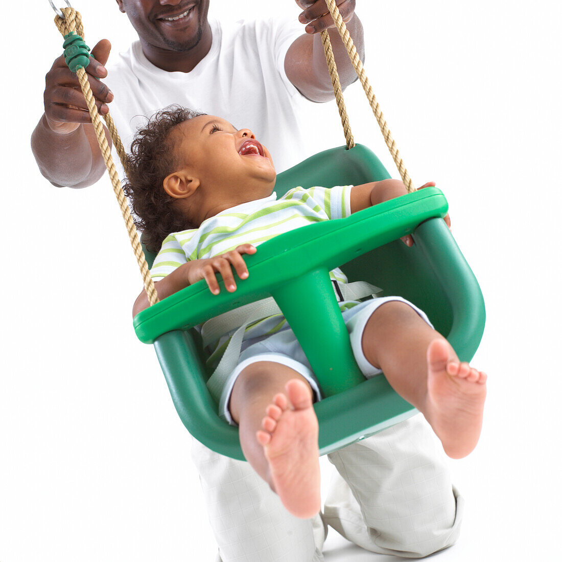 Father pushing toddler son on swing