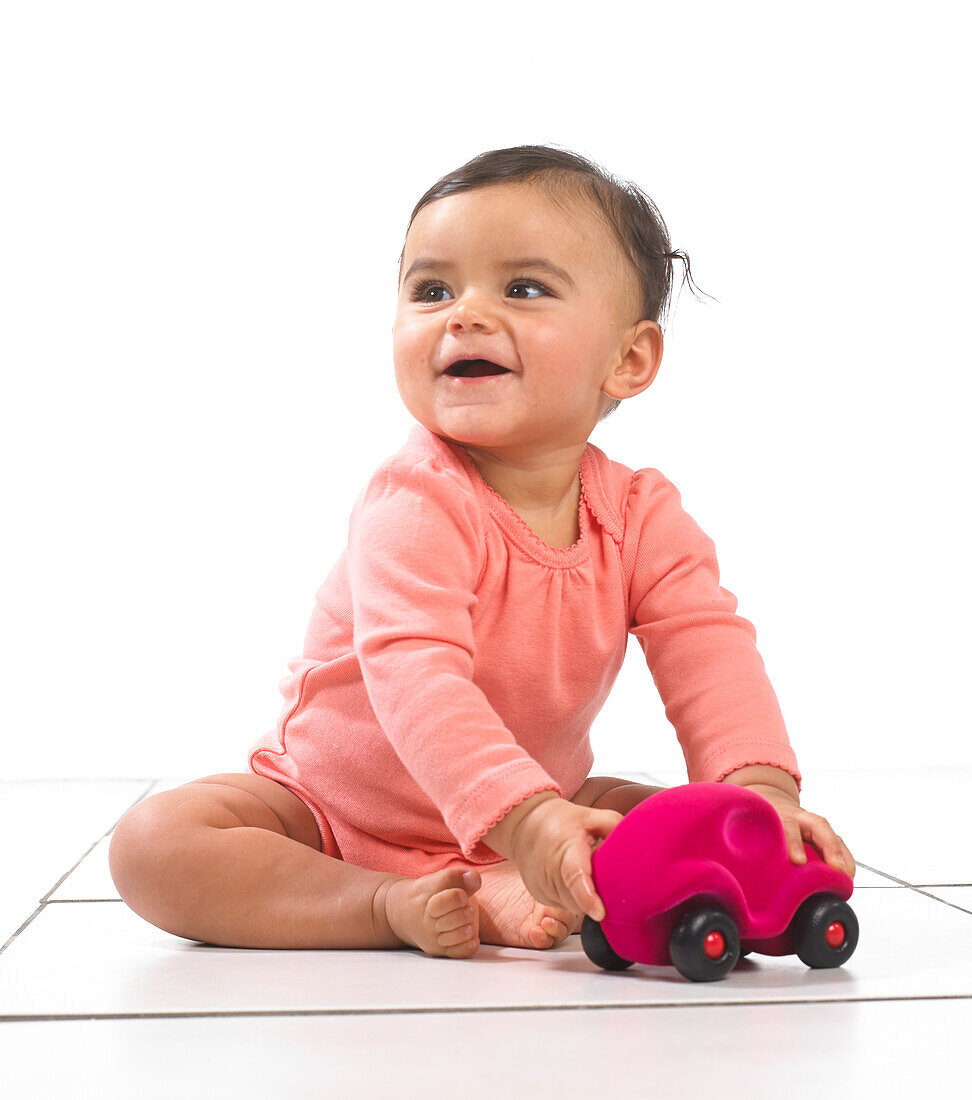 Baby girl sitting playing with a toy car