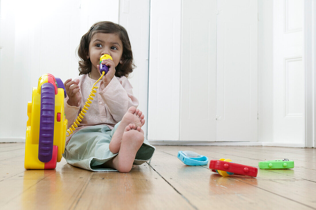 Girl sitting on the floor playing with plastic toy