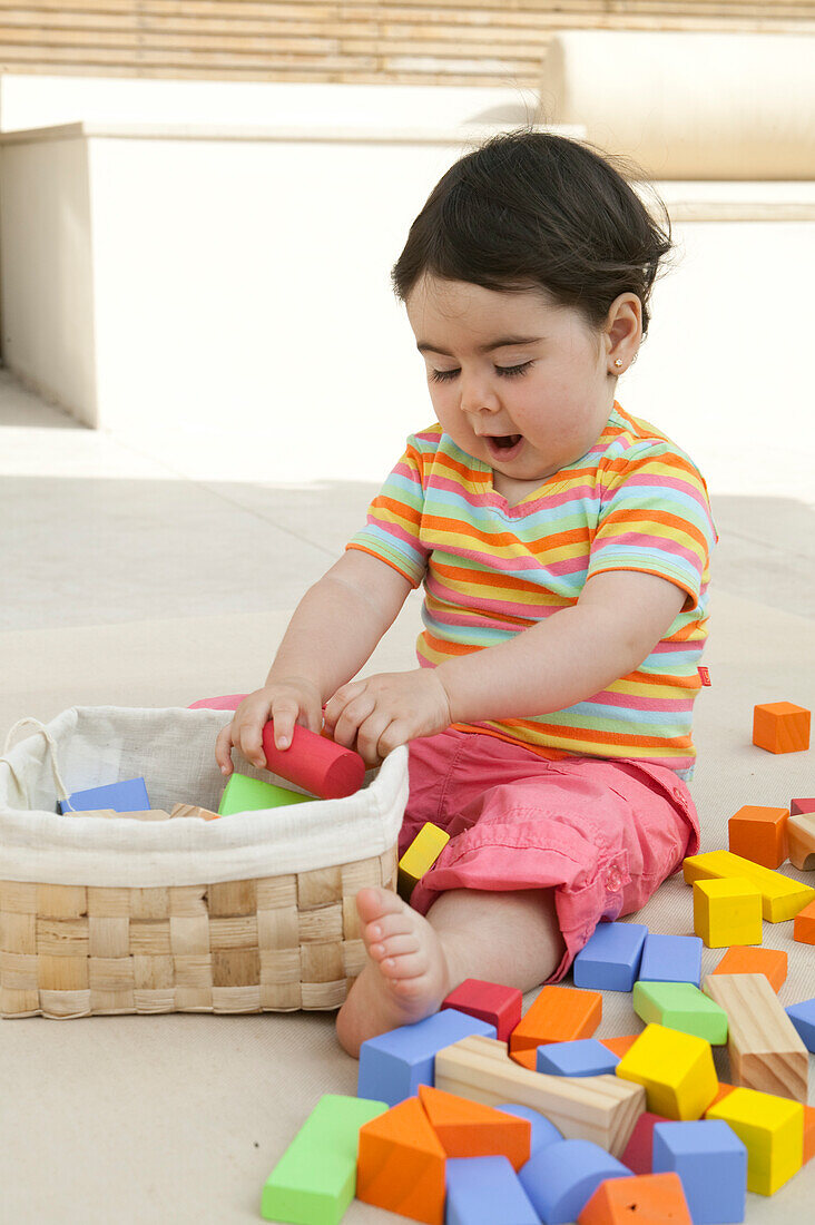 Baby girl putting toy bricks in a basket