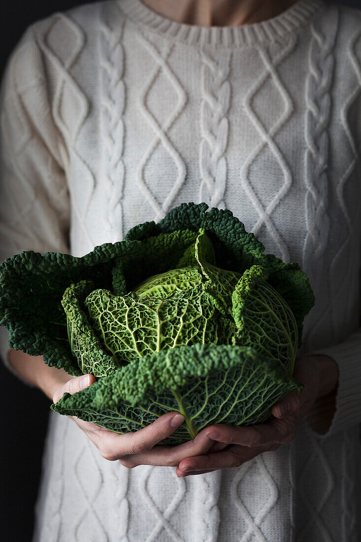 A cook holding a fresh cabbage
