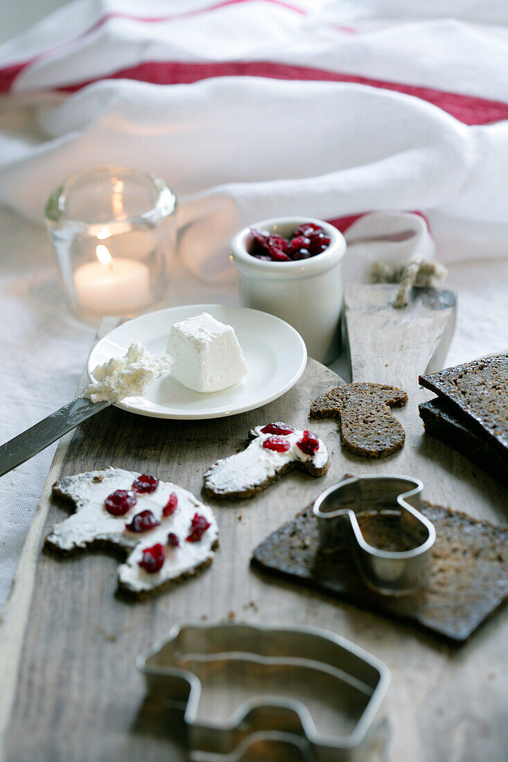 Bread with cream cheese and pomegranate seeds, tea light and cookie cutters