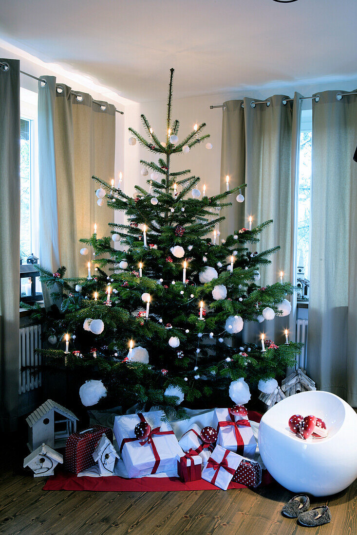 Weihnachtlich geschmückter Tannenbaum mit Geschenken im Wohnzimmer