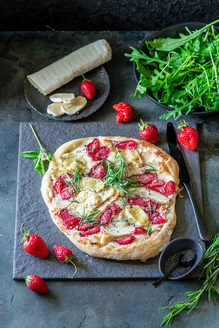Strawberry pizza with chicken fillet, brie, poppy seeds, rosemary, and rocket salad