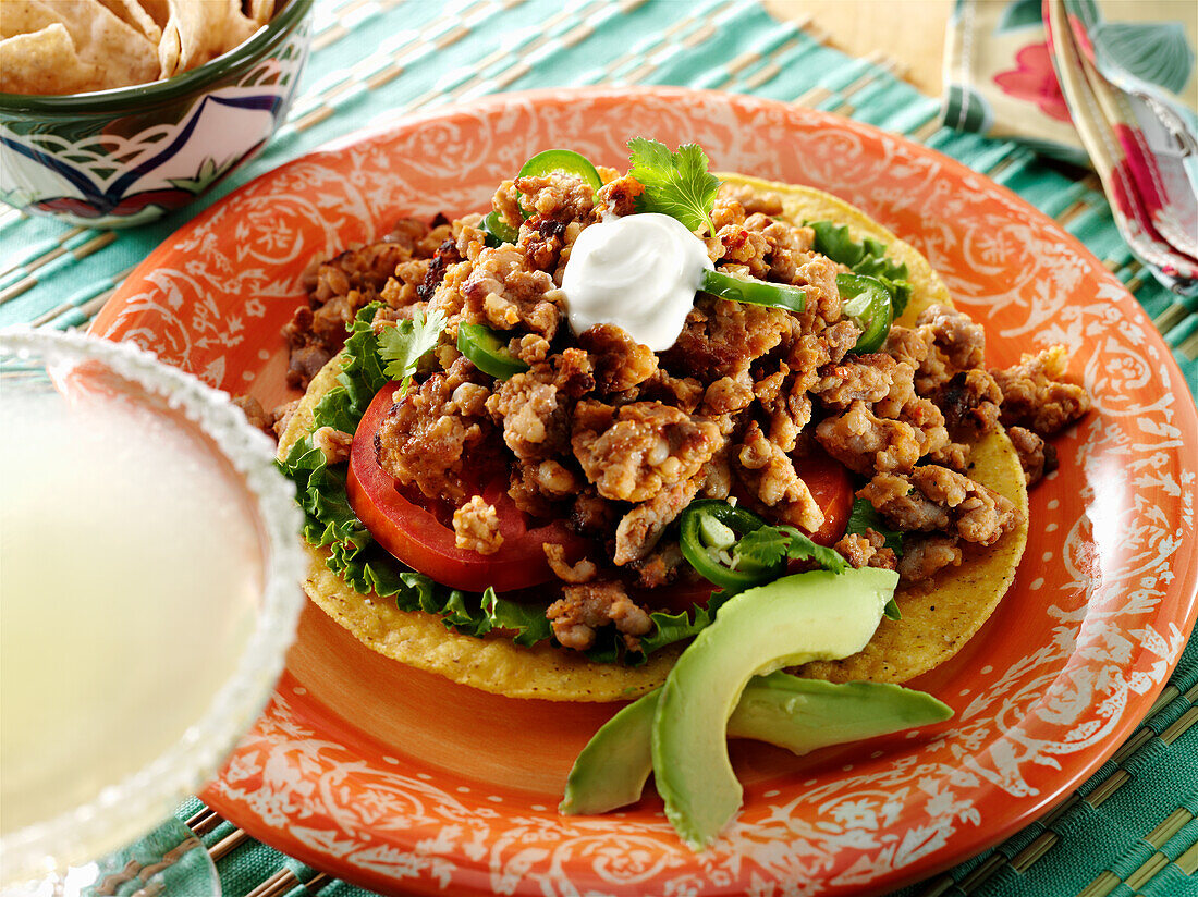 Chorizo-Tostada mit Salat, Tomate, Koriander, Jalapeno und Avocado