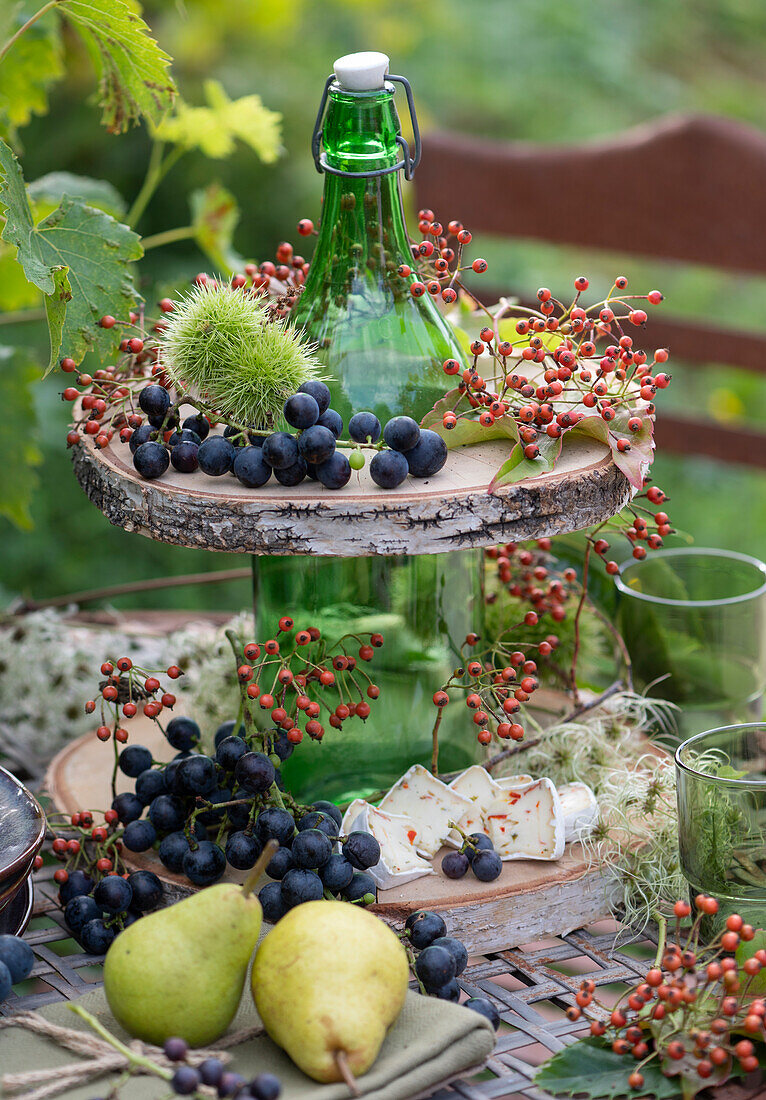 Make your own etagere out of a bottle and wooden discs: blue grapes, cheese, pears, rose hips and chestnuts in a fruit cover