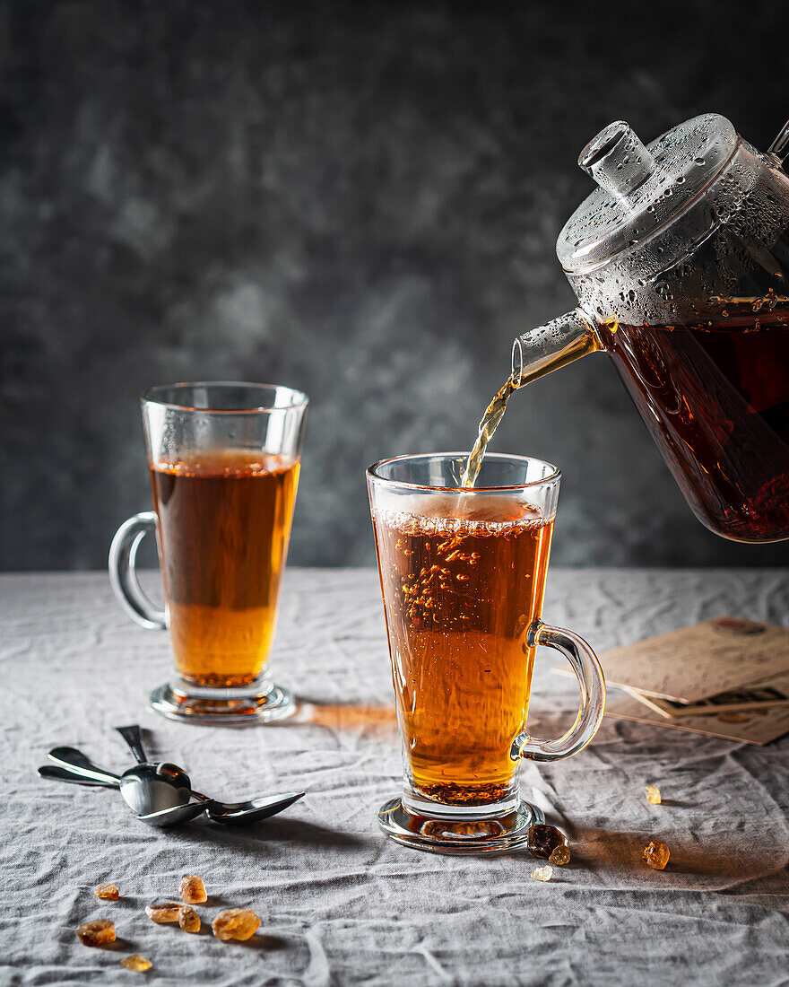 Pour rooibos tea from a glass jug into a tea mug