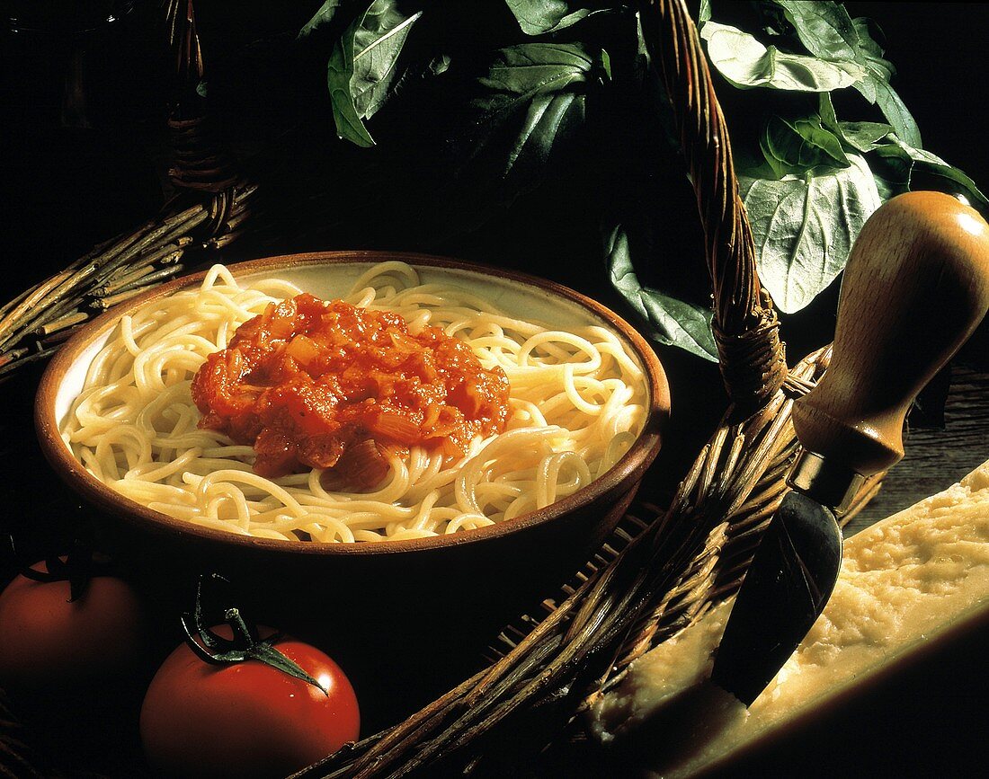 Spaghetti mit Tomatensauce in Schüssel, Deko: Basilikum