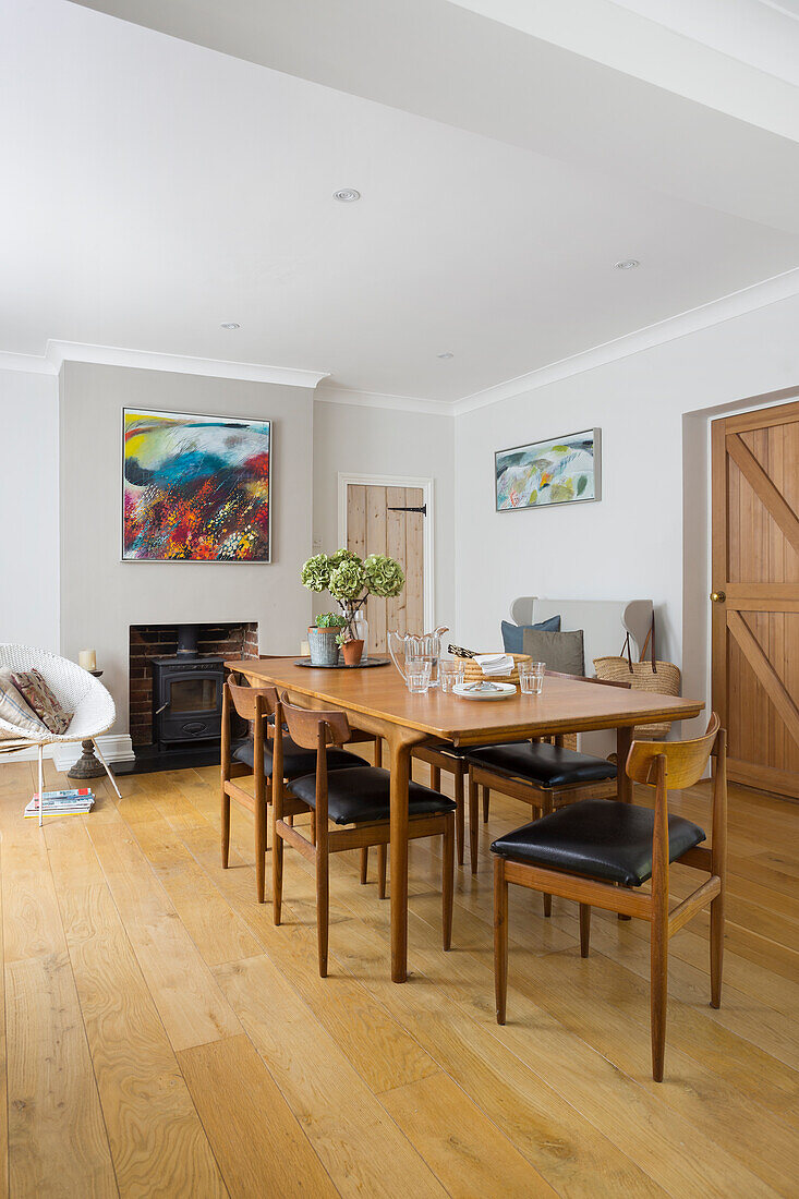 Dining area with vintage furniture and modern artwork above wood-burning stove