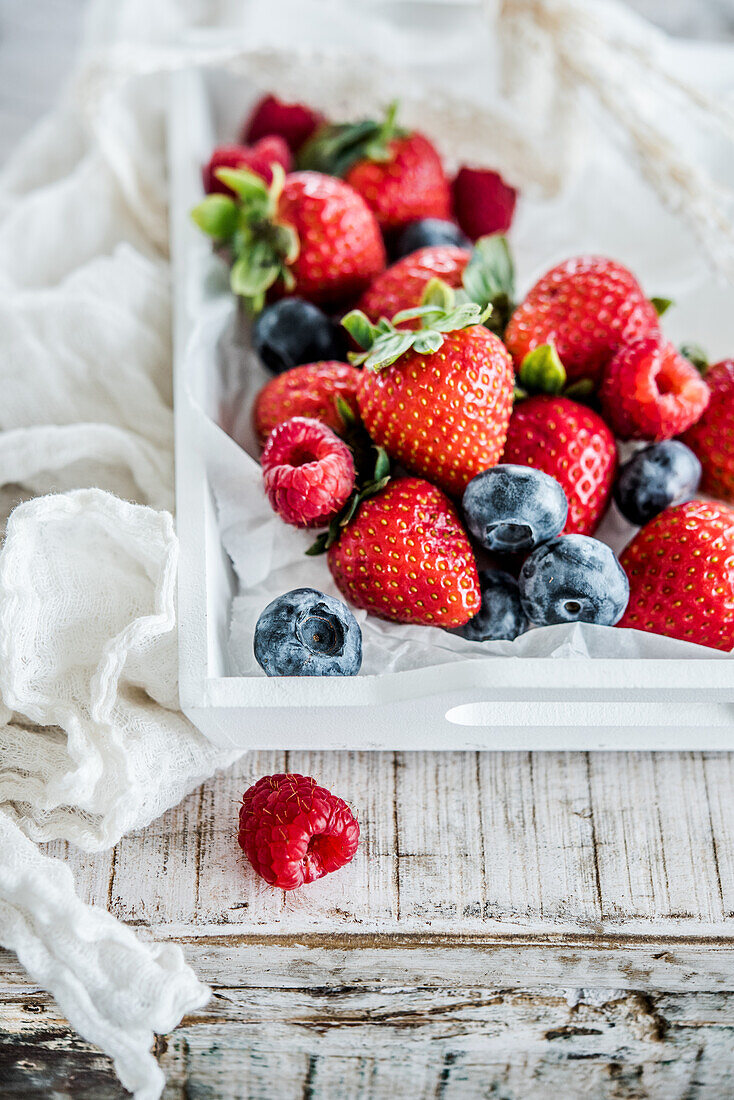 Strawberries, raspberries and blueberries on a white tray
