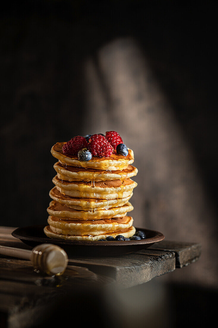 Ein Stapel Pancakes mit Beeren und Honig
