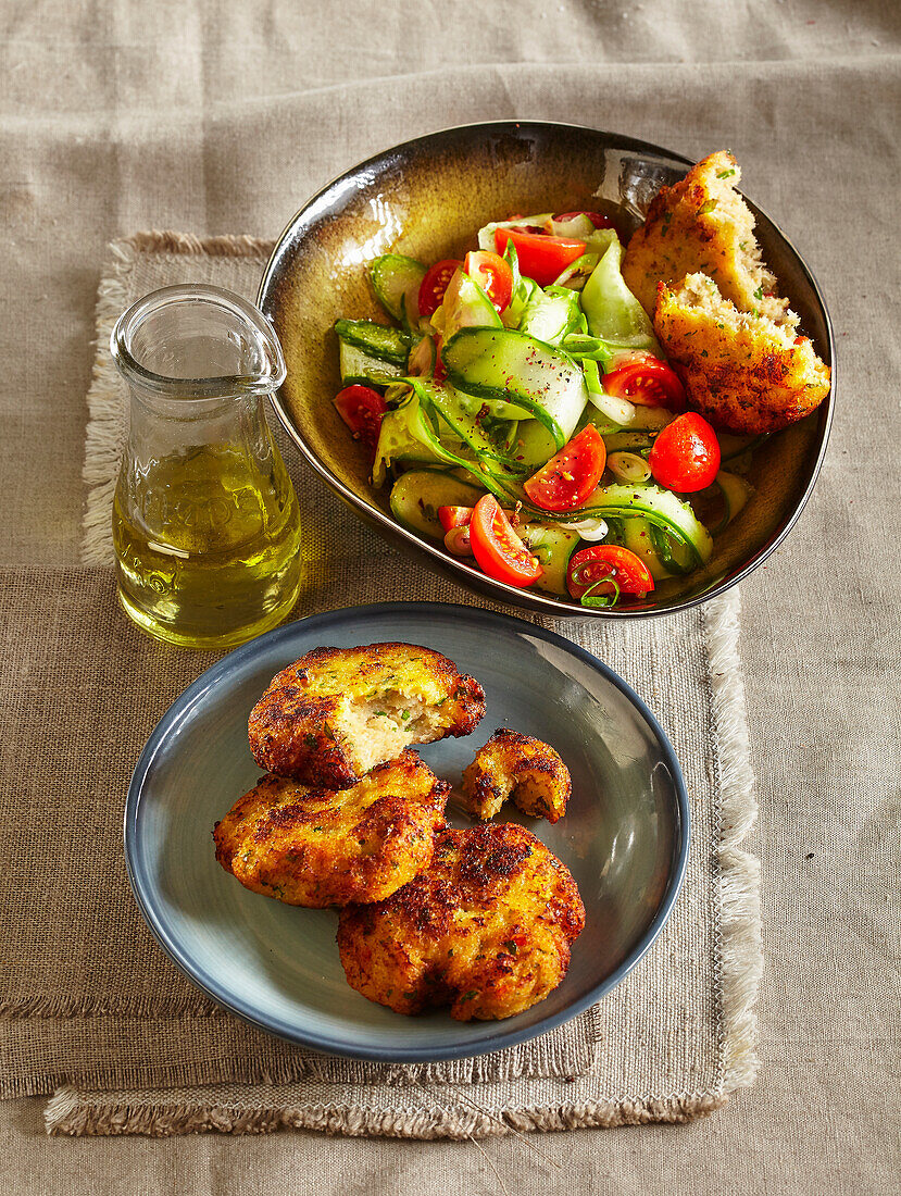 Fish cakes served with cucumber and tomato salad