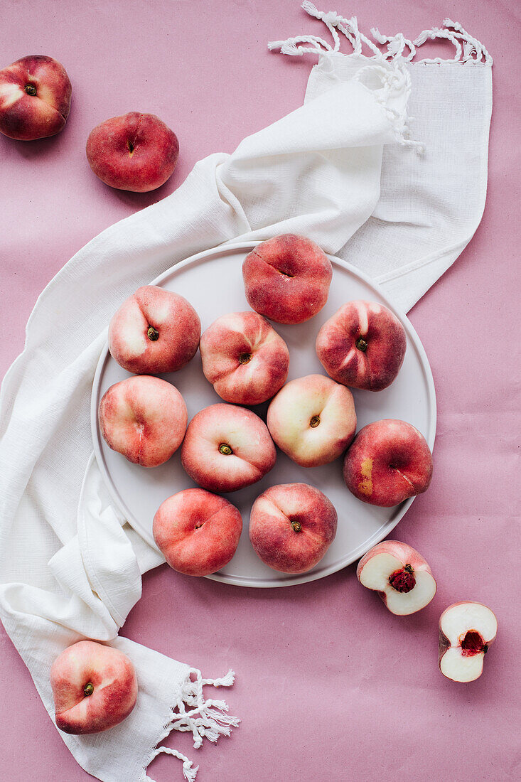 Weiße Pfirsiche auf Teller und rosa Untergrund