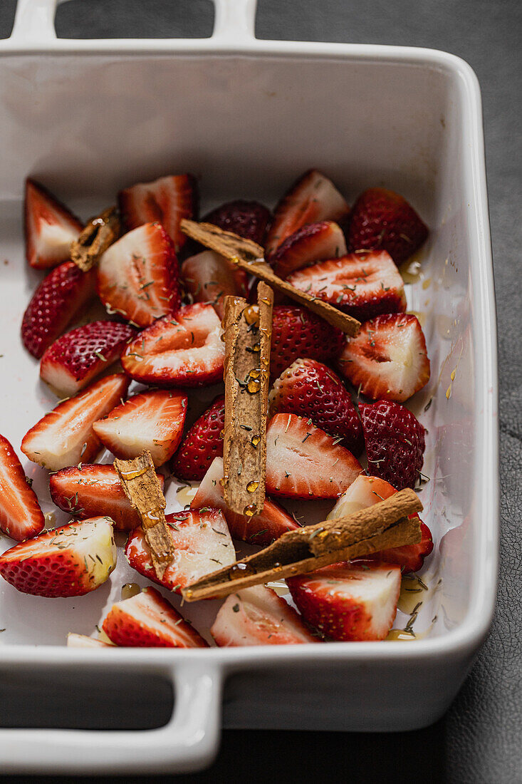Cut strawberries with a cinnamon stick and fresh thyme leaves