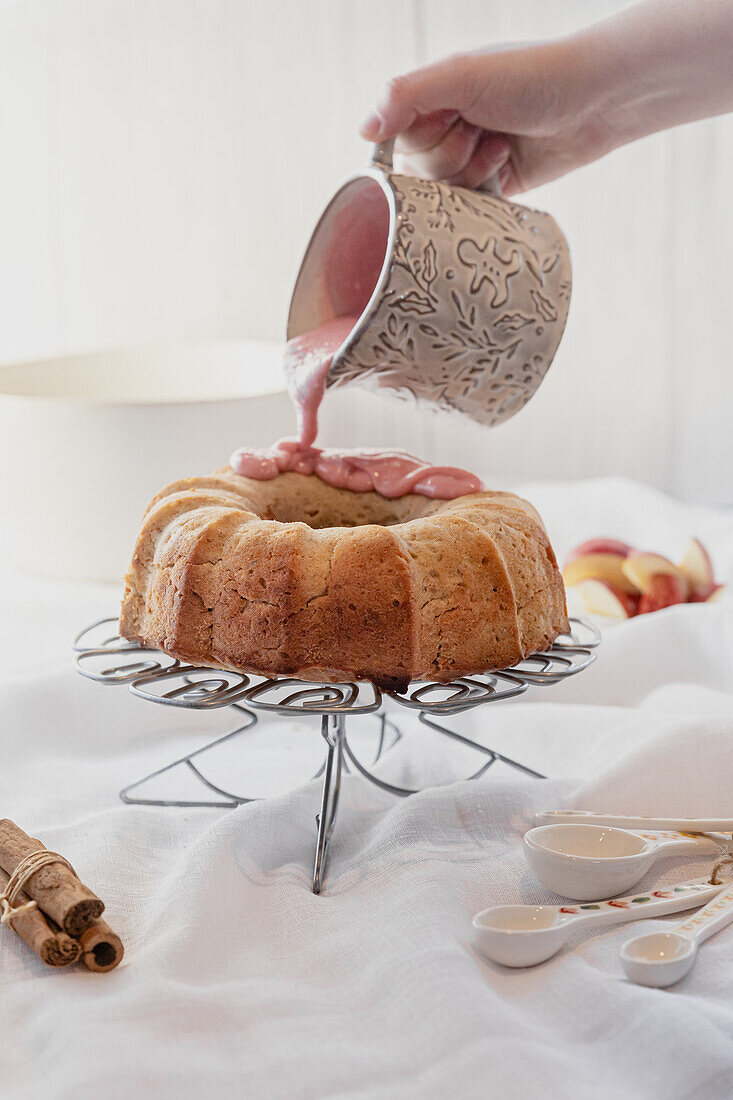 Apple bundt cake with pink Pomegrante glaze being poured