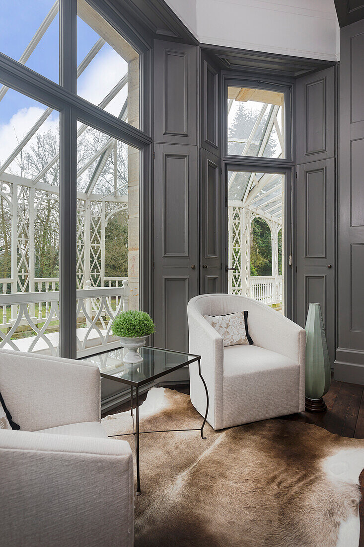 Club chairs with white upholstery and glass table next to window