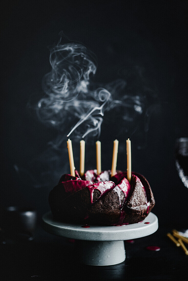 Schokoladen-Kranzkuchen mit Himbeerglasur und ausgepusteten Kerzen