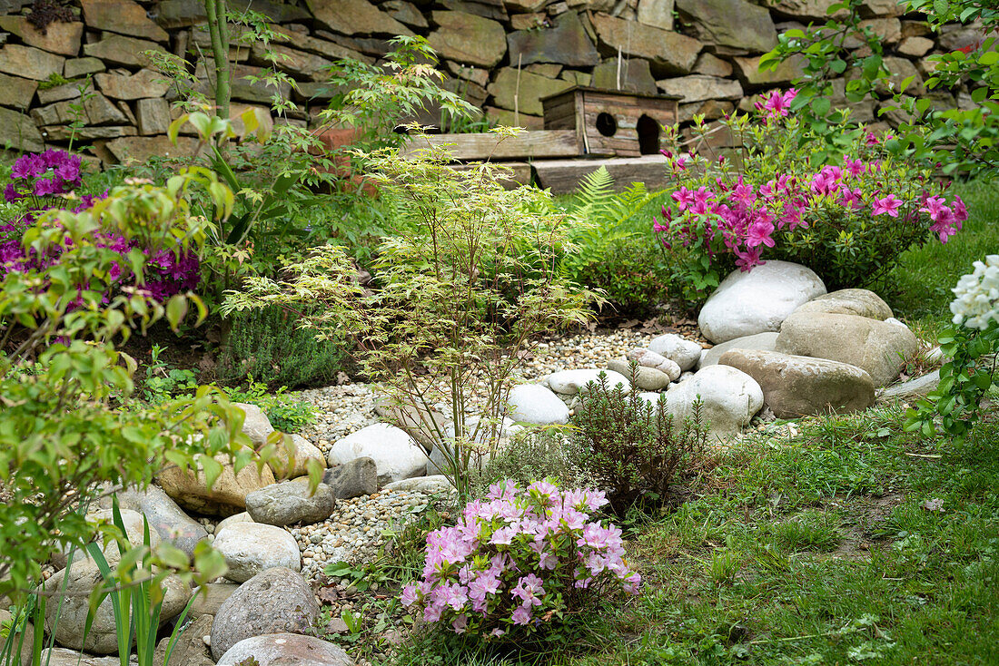 Üppig bewachsener Sommergarten mit Natursteinen und Trockensteinmauer