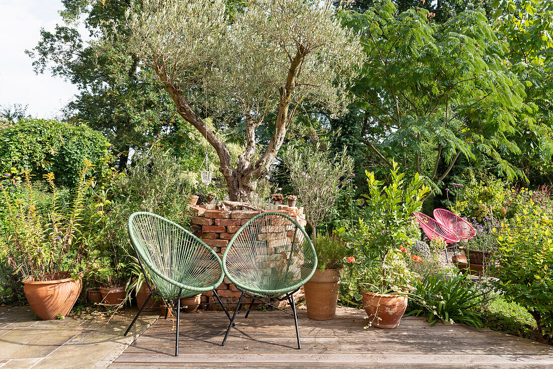 Two chairs on a sunny terrace in front of a garden