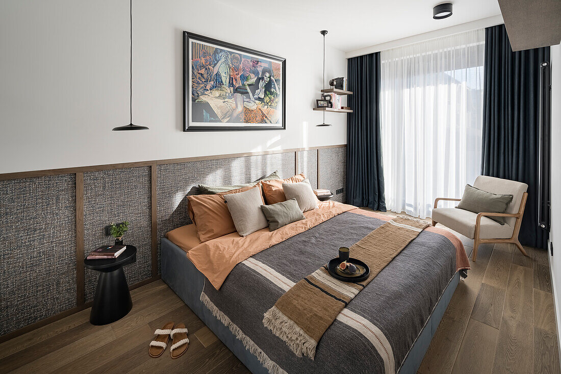 Double bed with scatter cushions against panelled wall in bedroom