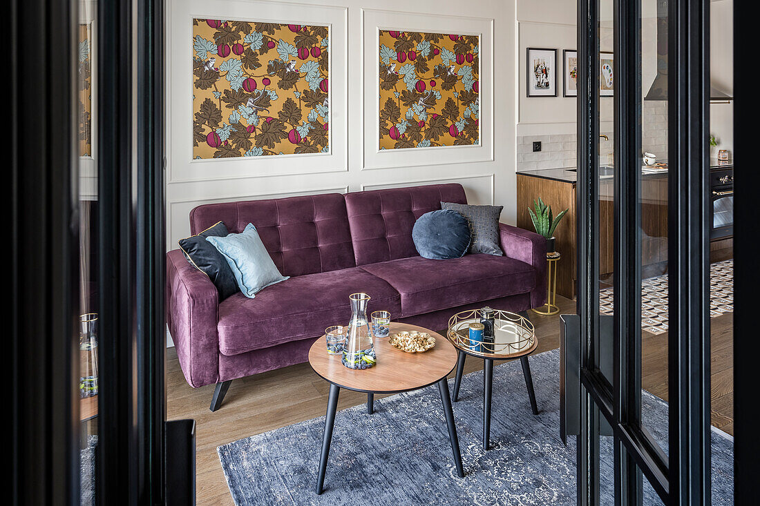 Blick durch geöffnete Glastüren auf lila Sofa und Couchtisch-Set in offenem Wohnraum